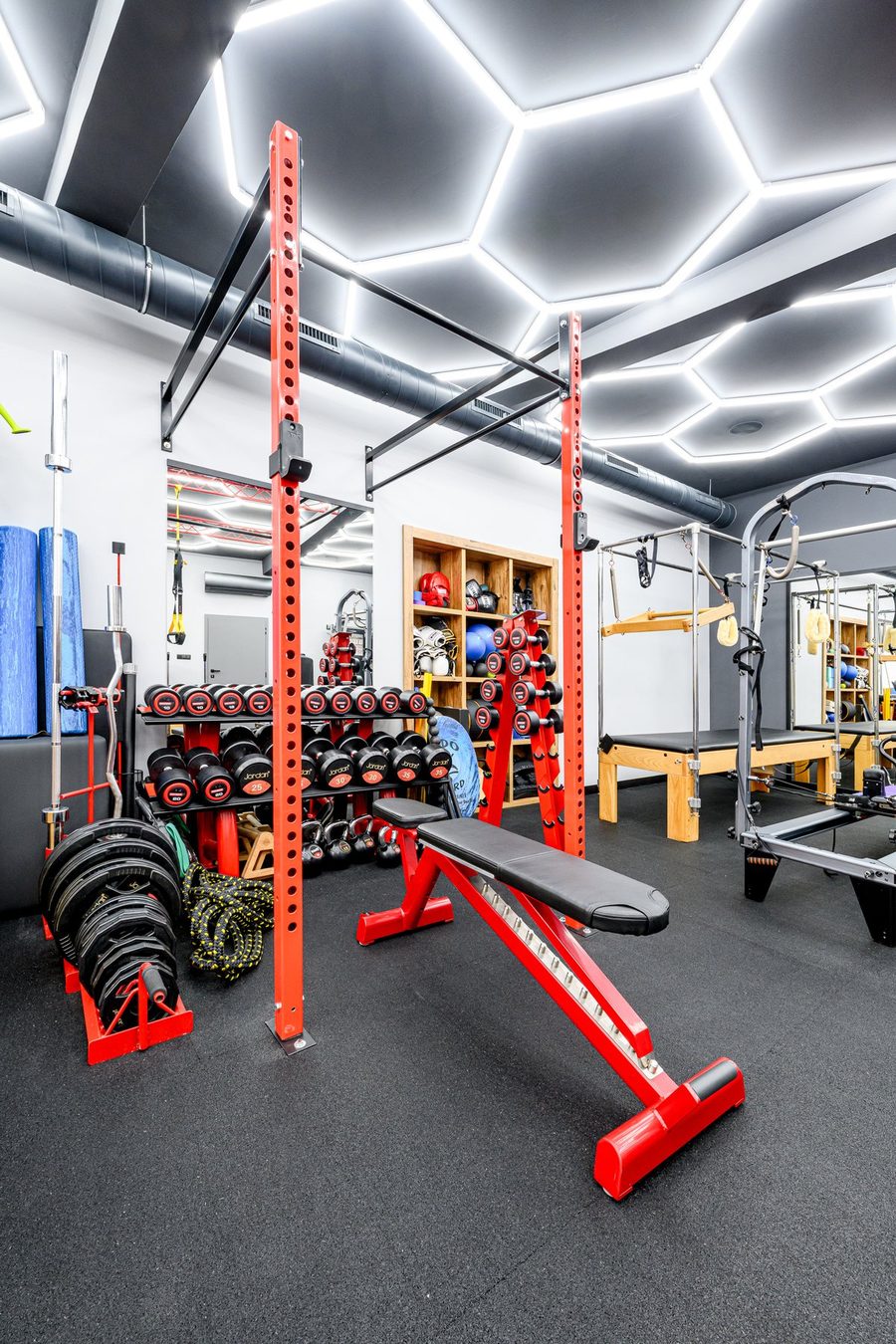 Silová a funkční zóna ve Fit Pilates studiu Praha 10 — TuffStuff squat rack, Jordan činky, TRX, kettlebelly